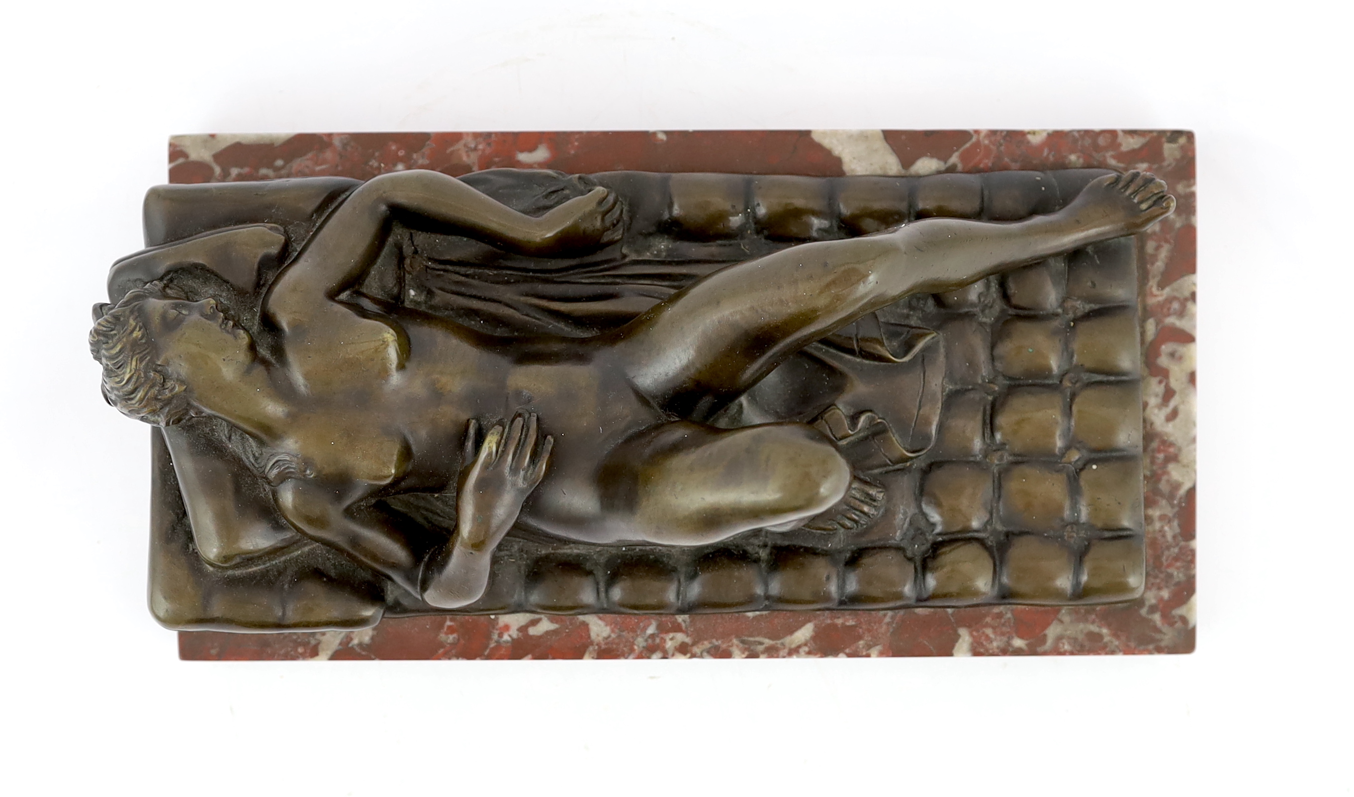 A late 19th/early 20th century bronze female nude reclining on a bed, on a red marble base, 32cm long